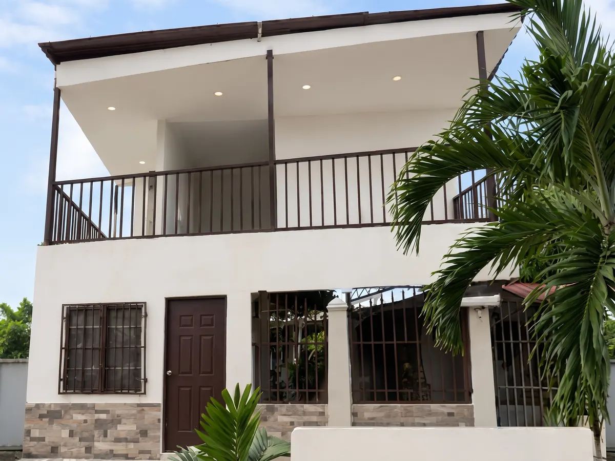 Vivienda con un segundo nivel nuevo, balcón con baranda y fachada con zócalo en piedra