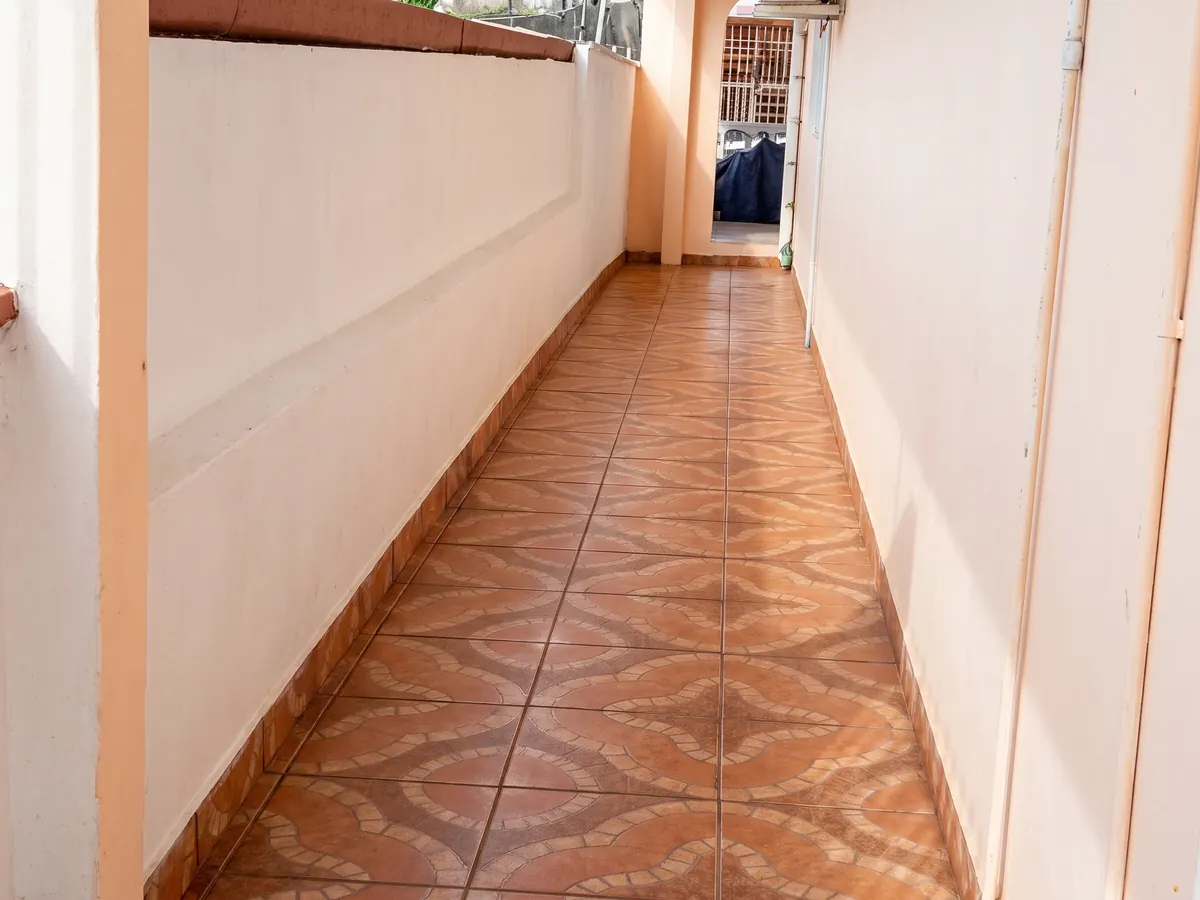 Pasillo lateral con piso enchapado y paredes resanadas y pintadas